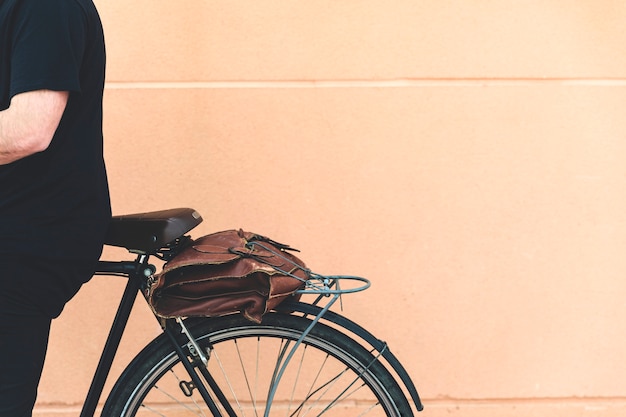 Foto gratuita primer plano de un hombre sentado en bicicleta contra la pared beige