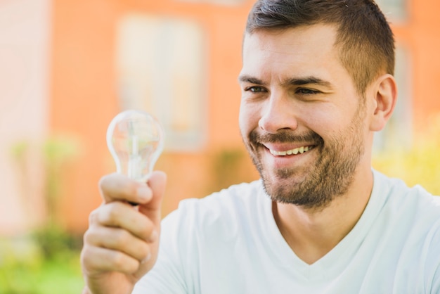 Primer plano de hombre sonriente con bombilla transparente