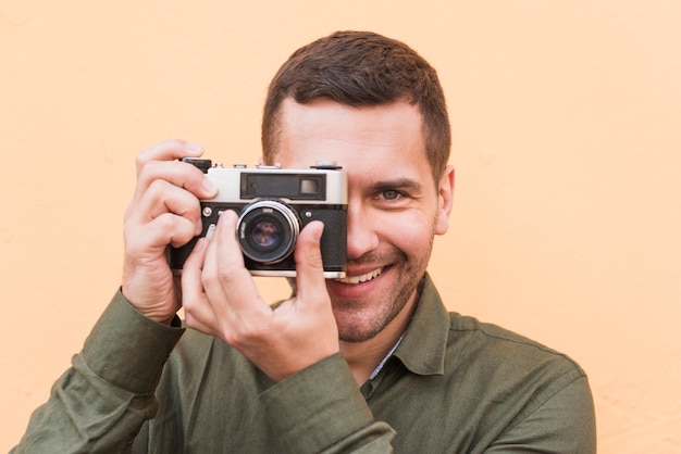 Primer plano de hombre sonriente tomando foto con cámara