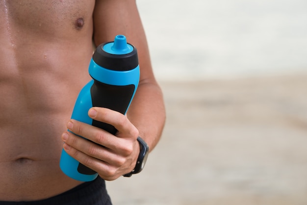 Primer plano de hombre sosteniendo la botella de agua al aire libre