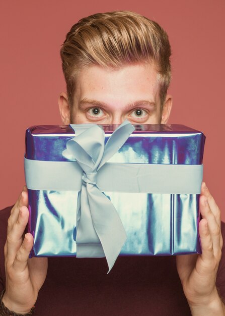 Primer plano de hombre sosteniendo la caja de regalo envuelto debajo de los ojos