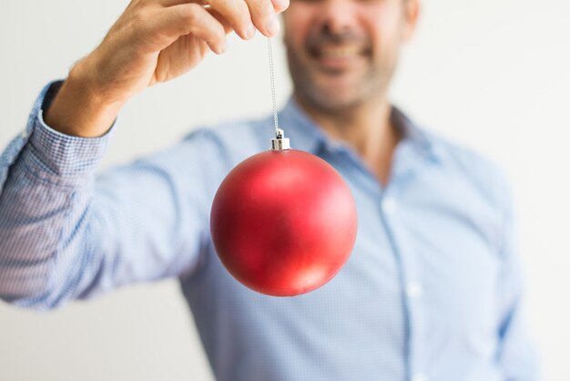 Primer plano de hombre sosteniendo una cuerda de bola de Navidad y viéndola