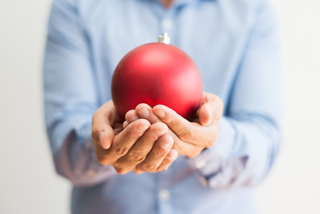 Primer plano de hombre sosteniendo hermosa bola roja de Navidad