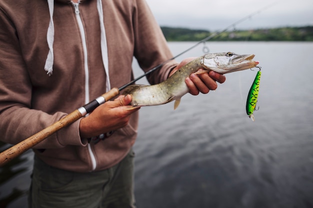 Foto gratuita primer plano de hombre sosteniendo pescado recién capturado con señuelo