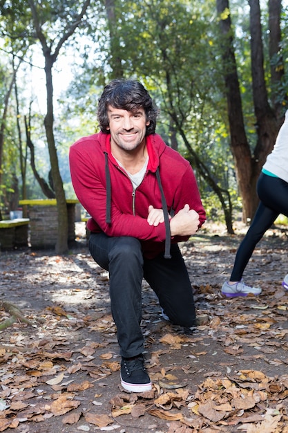 Primer plano de hombre con sudadera roja estirando sus piernas