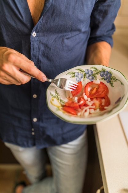 Primer plano, de, hombre, tenencia, rebanada de tomate, con, tenedor