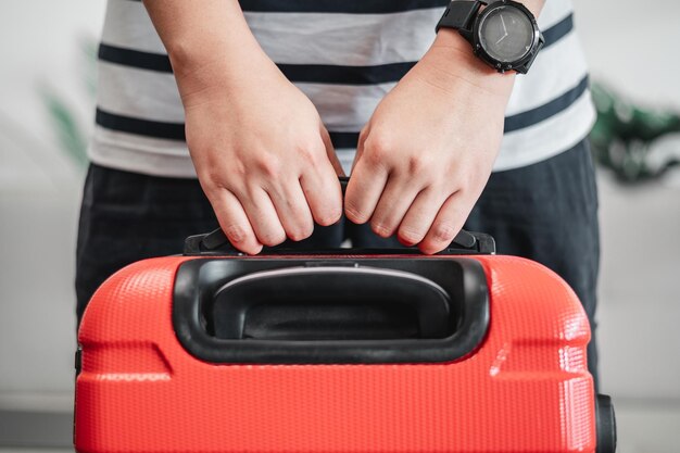 Primer plano del hombre tocando el equipaje El joven ha empacado su equipaje y está listo para viajar Concepto de vacaciones y vacaciones