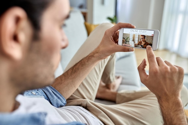 Primer plano de un hombre usando un teléfono móvil y eligiendo un programa de estudio para eleaning desde casa