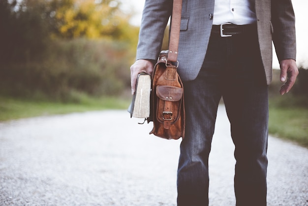 Primer plano de un hombre vestido con un traje de negocios y de pie mientras sostiene la Biblia