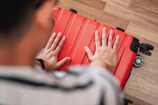 El primer plano del hombre viajero ha terminado de empacar y los está bloqueando El hombre está preparando ropa en maletas Concepto de vacaciones y vacaciones de viaje