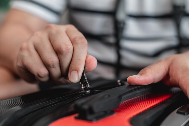 El primer plano del hombre viajero ha terminado de empacar y los está bloqueando El hombre está preparando ropa en maletas Concepto de vacaciones y vacaciones de viaje