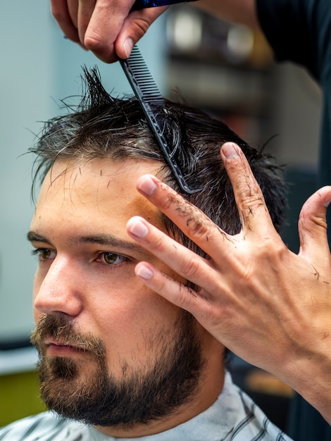 Primer plano del hombre de la vista lateral que consigue corte de pelo profesional