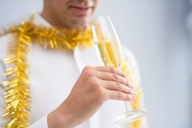 Primer plano de hombre vistiendo oropel y bebiendo champán