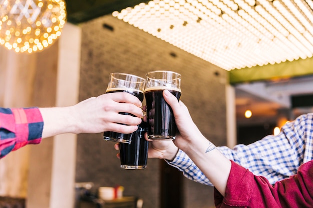 Primer plano de hombres tintineando los vasos de cerveza en pub