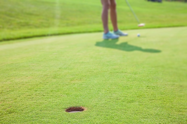 Primer plano de un hoyo en el green en el campo de golf Zlati Gric en Eslovenia con un golfista