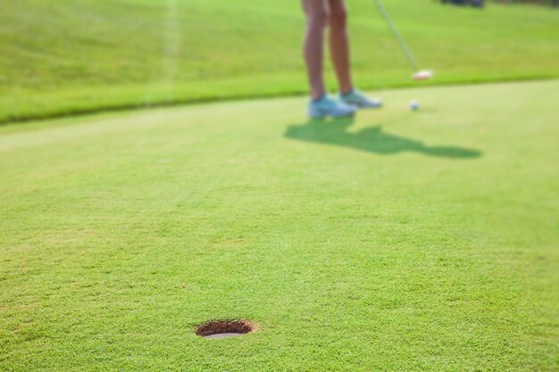 Primer plano de un hoyo en el green en el campo de golf Zlati Gric en Eslovenia con un golfista