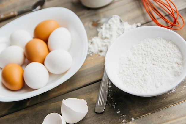 Primer plano de los huevos y la harina en el escritorio de madera