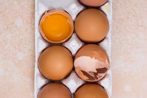 Primer plano de huevos rotos en cartón blanco sobre fondo de textura