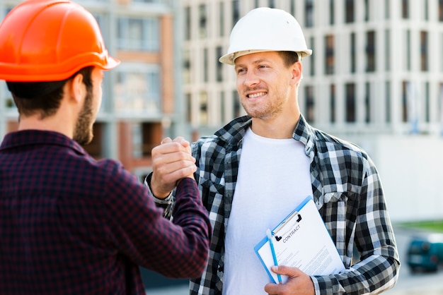 Primer plano de ingeniero y arquitecto dándose la mano