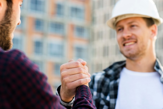 Primer plano de ingeniero y arquitecto dándose la mano