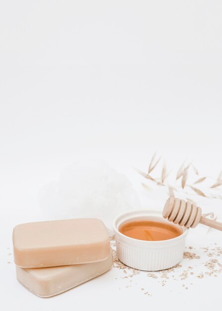 Primer plano de jabón; miel; cucharón de miel y esponja vegetal sobre fondo blanco