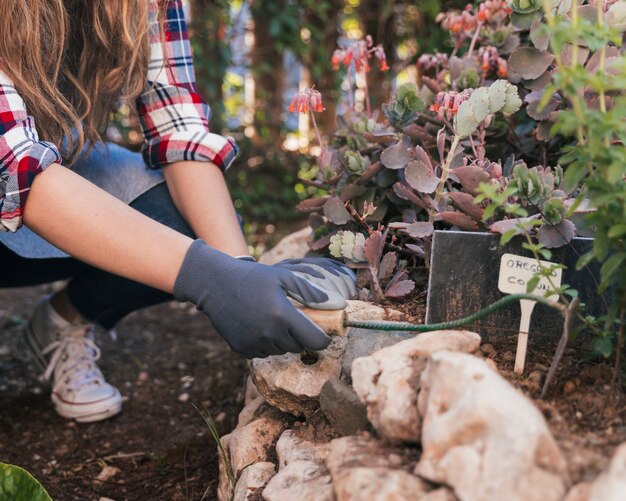 Foto gratuita primer plano de un jardinero de sexo femenino que cava el suelo con la azada de mano en el jardín