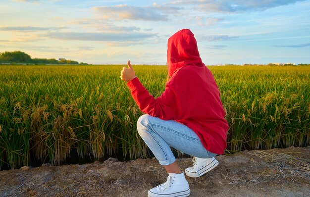 Primer plano de una joven dama en rojo alegremente junto a un campo verde en un día soleado