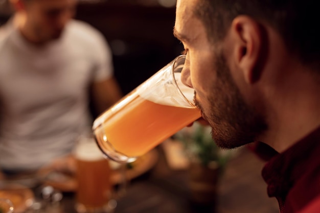 Primer plano de un joven degustando cerveza lager en un pub