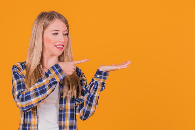 Primer plano de una joven empresaria apuntando a algo en mano contra el fondo de color