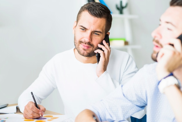 Primer plano de un joven empresario hablando por teléfono móvil