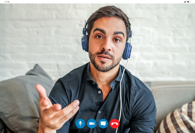 Primer plano de un joven empresario con una videollamada de trabajo mientras se queda en casa. Nuevo estilo de vida normal. Concepto de negocio.