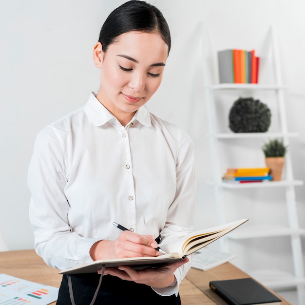 Primer plano, de, un, joven, mujer de negocios, escritura, en, diario, con, pluma