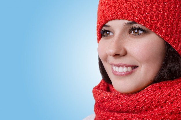 Un primer plano de una joven mujer de ojos marrones con una agradable sonrisa agradable con gorro con bufanda