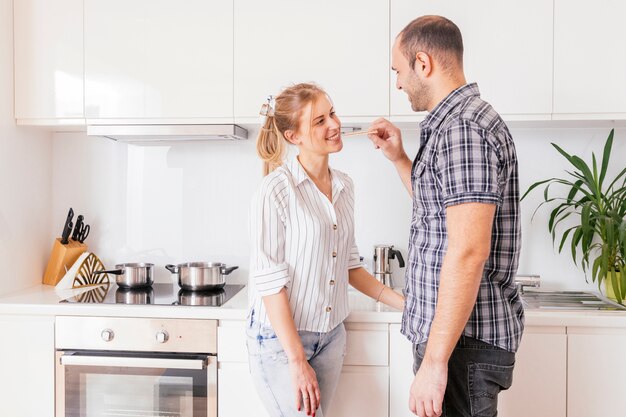 Primer plano de un joven que alimenta a su novia en la cocina.