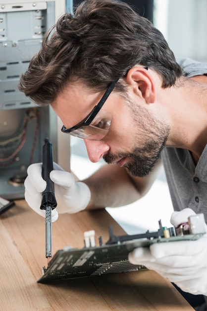 Foto gratuita primer plano de un joven técnico masculino que trabaja en la placa base del ordenador