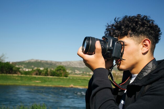 Primer plano de un joven tomando fotos con la cámara réflex digital