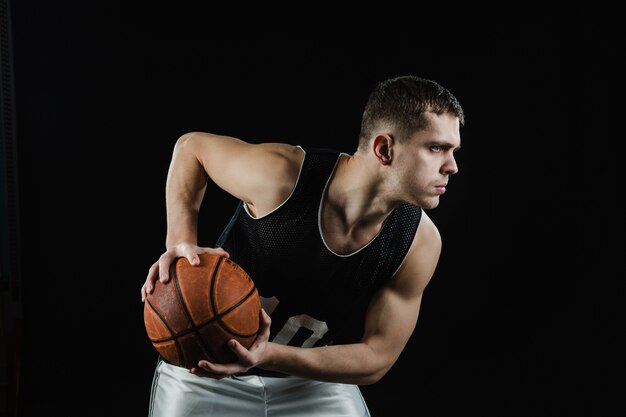 Primer plano de jugador de baloncesto con pelota sobre fondo negro