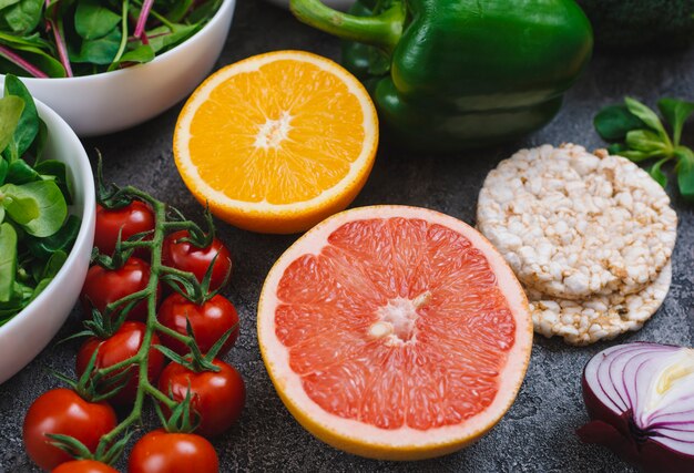 Primer plano de jugosas frutas cítricas a la mitad con verduras y pastel de arroz inflado