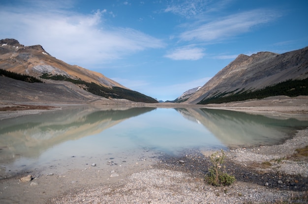 Primer plano de un lago rodeado de colinas rocosas