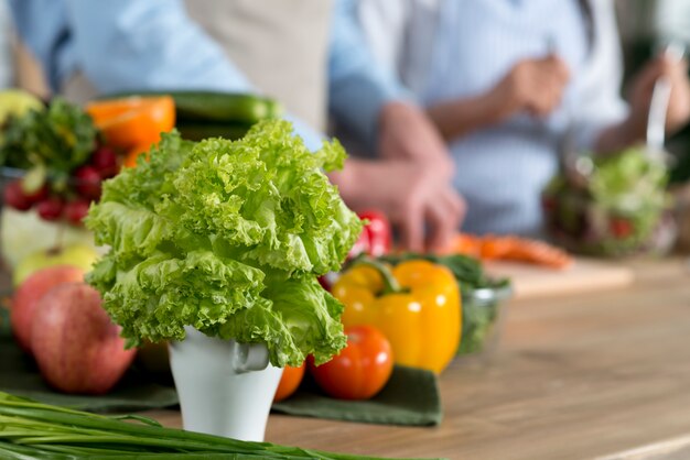 Primer plano de lechuga fresca verde en contenedor blanco en mostrador de madera