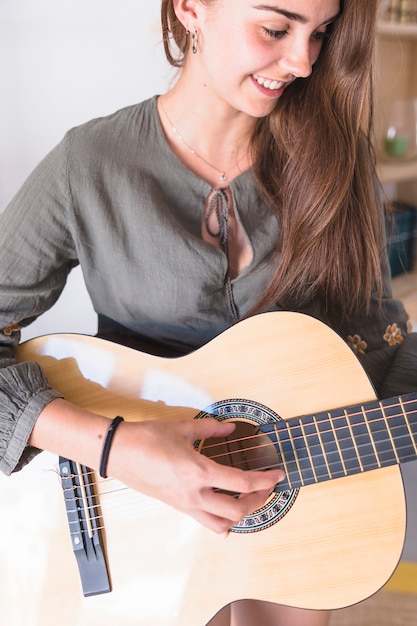 Primer plano de una linda adolescente tocando la guitarra