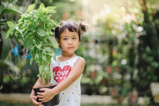 Primer plano de un lindo niño del sur de Asia sosteniendo una planta en un pa