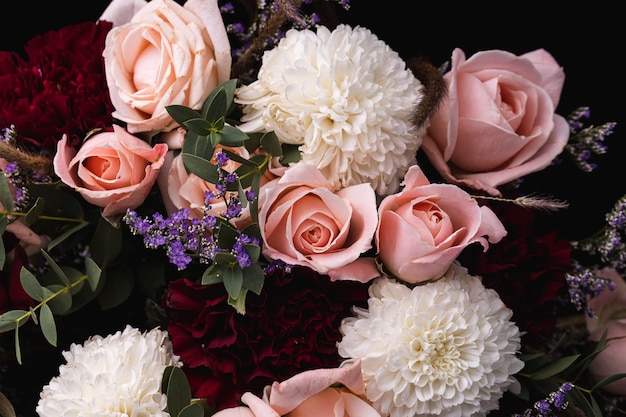 Primer plano de un lujoso ramo de rosas rosadas y flores blancas sobre un fondo negro