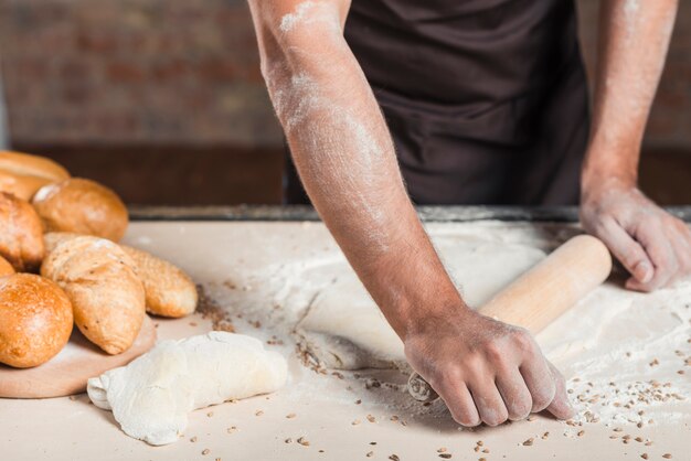 Primer plano, de, macho, panadero, aplanamiento, masa, en, cocina, worktop