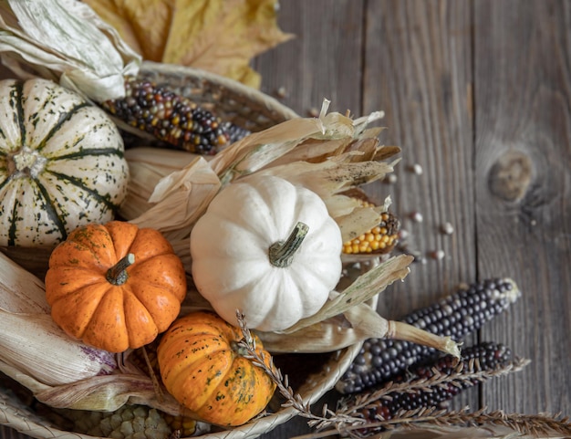 Primer plano de maíz calabaza y hojas de otoño sobre un fondo de madera