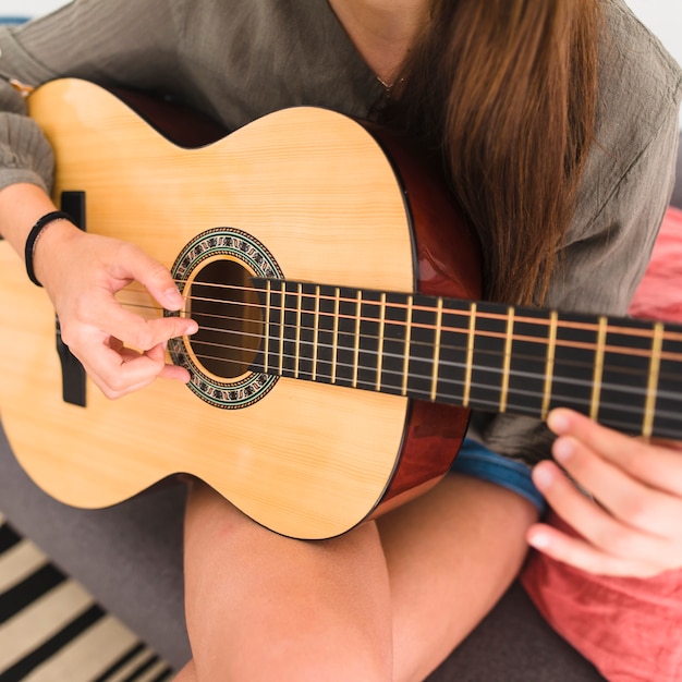 Primer plano de la mano de una adolescente tocando la guitarra