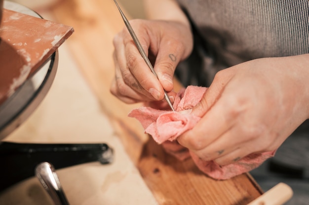 Primer plano de la mano del alfarero femenino limpiando la herramienta con la servilleta