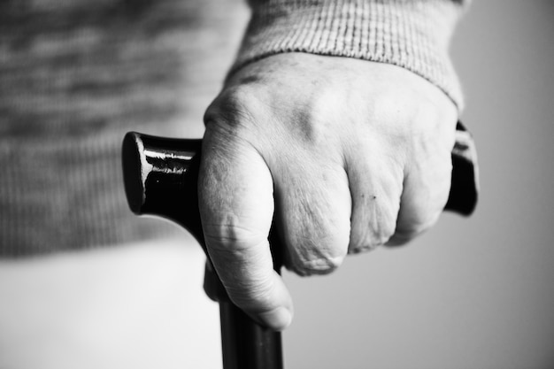 Primer plano de una mano anciana sosteniendo un bastón Foto gratis