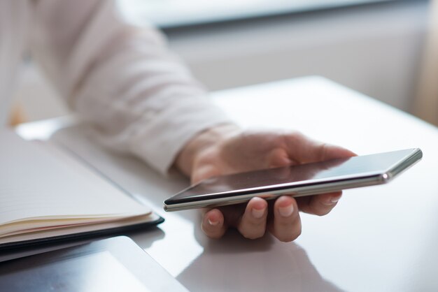 Primer plano de la mano de businesswomans sosteniendo teléfono móvil