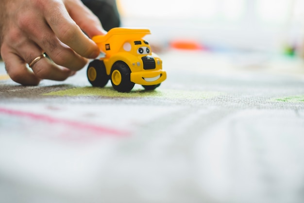 Primer plano de mano con un coche de juguete amarillo